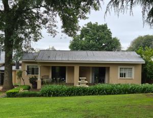 a small yellow house with a gray roof at Drinkwater Guest Farm in Grootgewaagd
