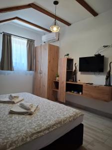 a bedroom with a bed and a tv on the wall at Fruškogorski Đeram in Grgeteg +4 photos