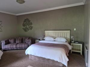 a bedroom with a large bed and a couch at Drinkwater Guest Farm in Grootgewaagd