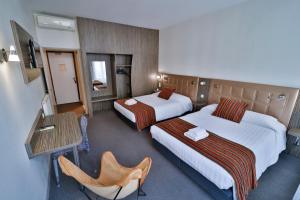 a hotel room with two beds and a table at Hôtel de l'Europe Grenoble hyper-centre in Grenoble