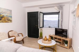 a living room with a couch and a tv and a window at The litlle mermaid in Amaliapoli