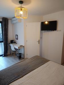 a bedroom with a bed and a desk and a chandelier at Villa'vi Lyon Est Chambres d'Hôtes in Saint-Priest