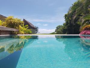 a swimming pool with blue water and palm trees at Bombua Beach House in Luganville