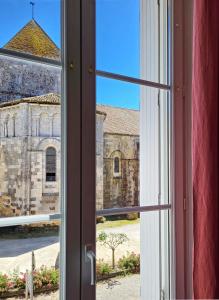 an open window with a view of a church at Une nuit à la Clouère in Saint-Maurice-la-Clouère +2 photos