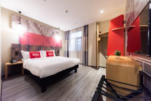a hotel room with a bed and a red wall at Ibis Yixing Longbeishan Forest Park in Yixing
