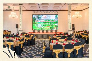 a banquet hall with tables and chairs and a projection screen at Phoenix Mộc Châu Resort in Mộc Châu +85 photos
