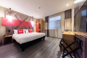 a hotel room with a bed and a flat screen tv at Ibis Yixing Longbeishan Forest Park in Yixing