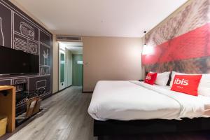 a hotel room with a large bed and a flat screen tv at Ibis Yixing Longbeishan Forest Park in Yixing +4 photos