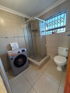 a bathroom with a shower and a washing machine at Shayas Haven in Thohoyandou +22 photos