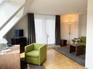 a living room with a green chair and a television at Seniorenresidenz am Tibusplatz in Münster