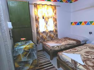 a room with two beds and a table in it at Shellaly Ca Nubian Guest2 House in Jazīrat Salūjah