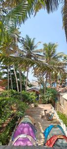 a group of tents on the beach with palm trees at Yog Inn in Varkala