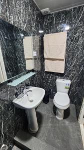 a bathroom with a white toilet and a sink at JONIKA Sleep & Go Inn in Aktepa-Chigatay +22 photos