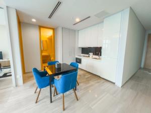 a kitchen and dining room with a table and blue chairs at UHF HOTELS and RESORTS PINETREE in Iskandar Puteri