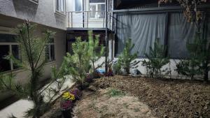 a garden in front of a building with trees and flowers at JONIKA Sleep & Go Inn in Aktepa-Chigatay