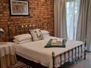 a bed in a bedroom with a brick wall at Green Haven Guest Lodge in Pretoria +79 photos