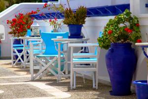 a row of chairs and tables and blue vases with plants at Samson΄s Village in Perissa