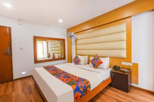a bedroom with a large bed with a wooden headboard at FabHotel Upstream Mysore Road in Bangalore