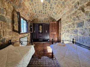 a bedroom with two beds in a stone wall at FARAYA à10 minutes in Ḩayy al Kanīsah