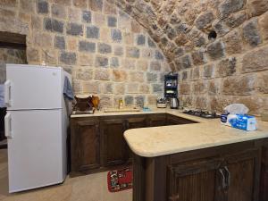 a kitchen with a white refrigerator and a stone wall at FARAYA à10 minutes in Ḩayy al Kanīsah +25 photos