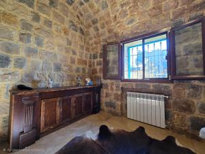 a stone walled room with a fireplace and a window at FARAYA à10 minutes in Ḩayy al Kanīsah