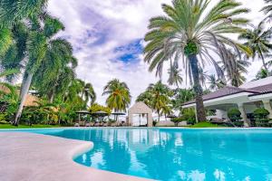 a swimming pool in front of a house with palm trees at Casa Negrense Private Resort in Dauin