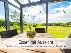 a conservatory with a table with a view of a garden at Huus Binnensee - Erdgeschoss-Wohnung mit Garten & Seeblick - Wintergarten & Terrasse - hundefreundlich - ruhige Lage - Südstrand 5 Min mit Rad in Fehmarn
