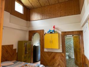 a room with wooden walls and a yellow cabinet at Kingdom Homestays in Manāli