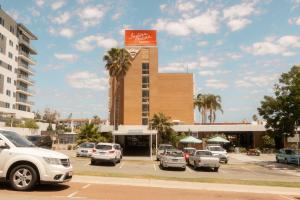 a parking lot with cars parked in front of a building at Indian Ocean Hotel in Perth