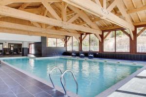 ein großes Hallenbad mit Holzdecken und ein großes Schwimmbecken in der Unterkunft Dormio Resort Les Portes du Mont Blanc in Vallorcine