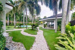 a tropical garden with palm trees and a walkway at Casa Negrense Private Resort in Dauin