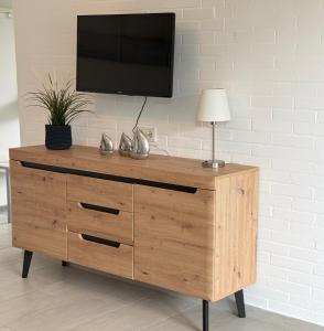 a wooden dresser with a television on a wall at Ferienhaus Wattglück Tossens in Butjadingen
