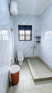 a white bathroom with a toilet and a shower at NL Josephine's Apartment in Kampala +10 photos