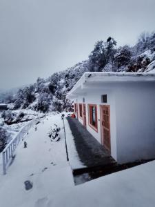 a house covered in snow next to a mountain at The Holiday Resort in Kailāna