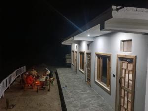 people sitting at tables outside of a building at night at The Holiday Resort in Kailāna +3 photos