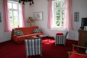 a living room with an orange couch and a table at Timmermannshof in Xanten