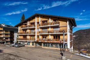a large wooden building with balconies and a parking lot at Appartement Tzoum'Azur 6 in La Tzoumaz