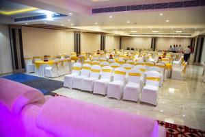 a room with rows of white chairs and tables at Comfort By Choice in Amritsar