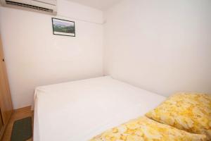 a small bedroom with a white bed and a pillow at Studio Marin in Baška +4 photos