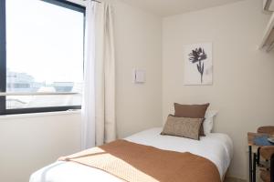 a white bedroom with a bed and a window at Mi-Hotel Nakano- Shinjuku Direct 中野南台 in Tokyo