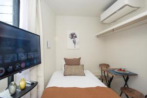 a bedroom with a large flat screen tv and a bed at Mi-Hotel Nakano- Shinjuku Direct 中野南台 in Tokyo