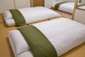 two beds in a room with green and white sheets at 白樺 l リノベーション済 l 千歳空港まで30分 l 貸切の一軒家 l 8名様までOK in Yuni