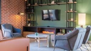a living room with two chairs and a fire place at Campanile NATURE - Lyon Est Bron Eurexpo in Bron