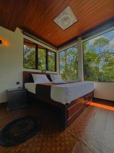 a bedroom with a large bed in a room with windows at Rainforest cabin in Deniyaya
