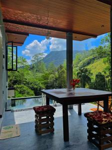 a table on a patio with a view of a mountain at Rainforest cabin in Deniyaya