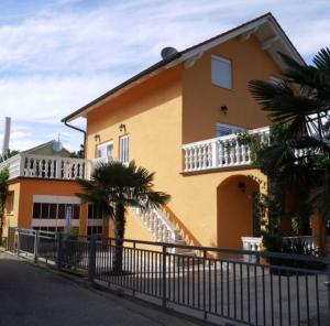 a yellow house with a balcony and palm trees at Villa Nikki in Bilice