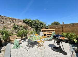 a patio with a table and chairs and a grill at L'Évasion Tropicale, Queen Size, Jardin & Gare in Saint-Brieuc