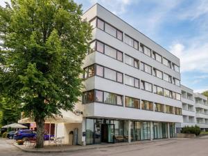 a white building with a tree in front of it at Carolina Hotel in Pärnu