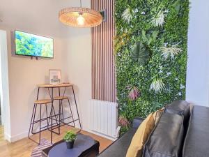 a living room with a green wall with plants at L'Évasion Tropicale, Queen Size, Jardin & Gare in Saint-Brieuc