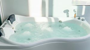 a bath tub filled with water with clouds in it at Gyeongju Modern Pool Villa in Gyeongju